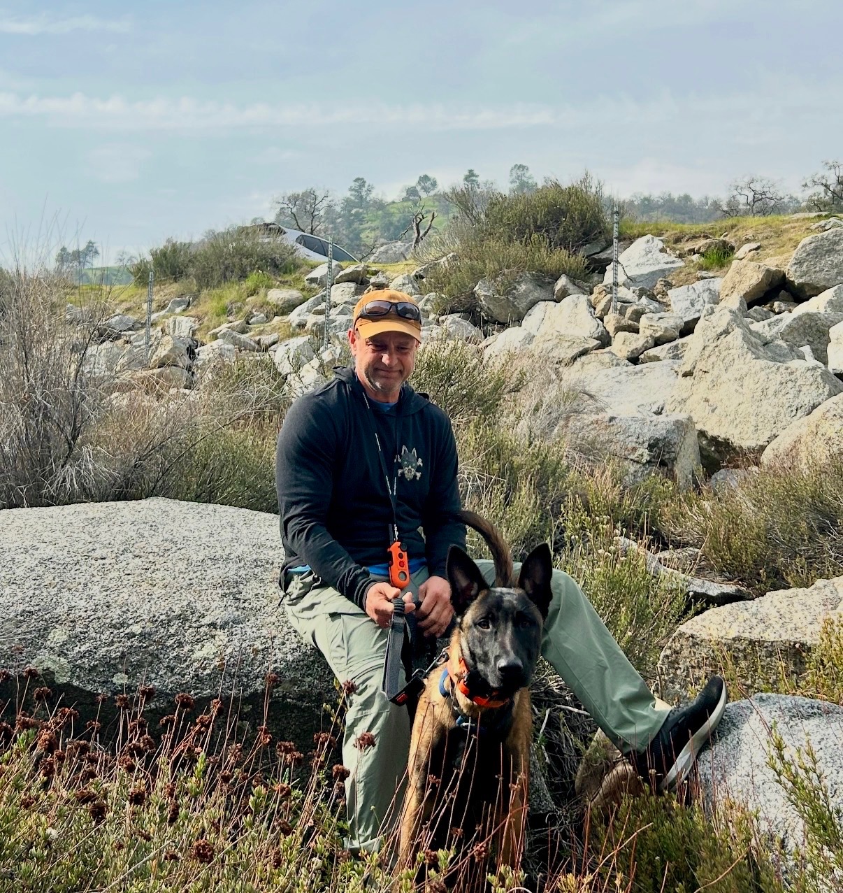 Trainer and dog on riverside rocks
